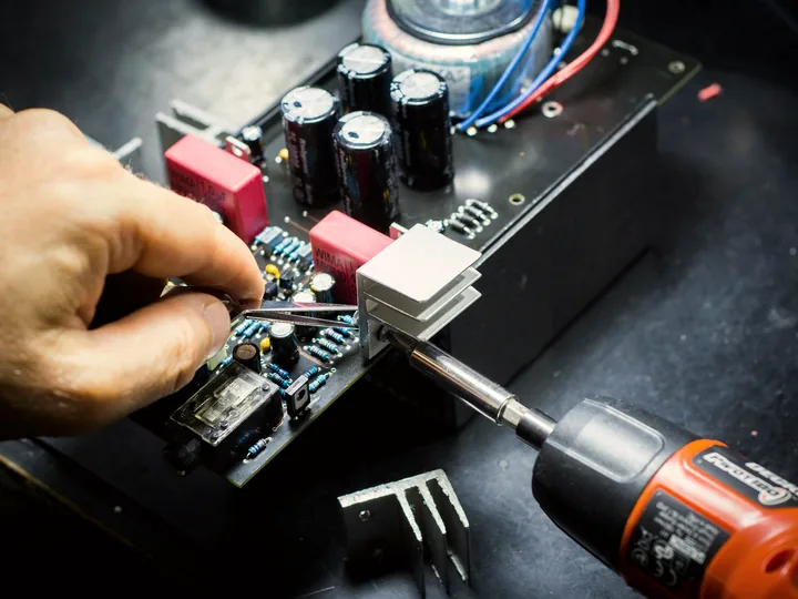 Mano che monta componenti su una scheda elettronica