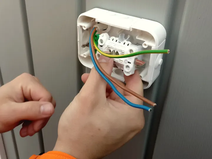Mani che collegano i conduttori di una presa elettrica